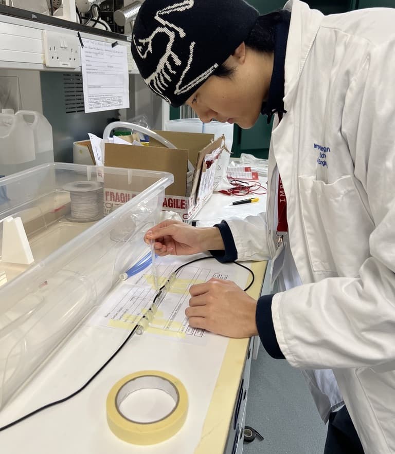 Placing the transducer leads against the acrylic flow chamber on the Dyson School lab bench.